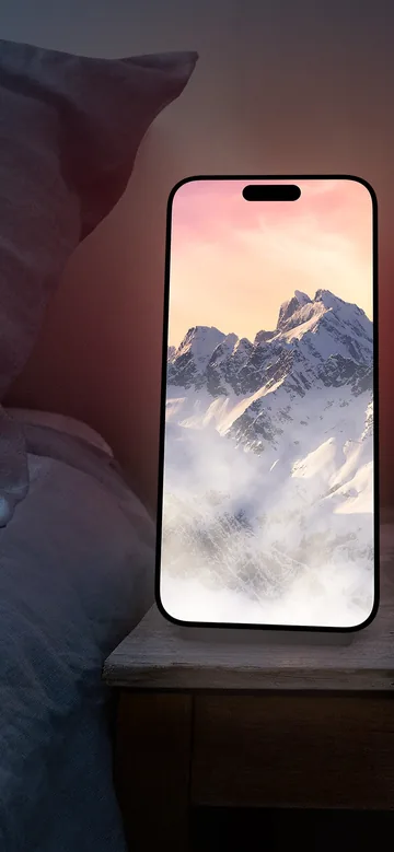 Visuel officiel de Night Light montrant un paysage de montagnes animé sur l’écran d’un iPhone posé près d’un lit.
